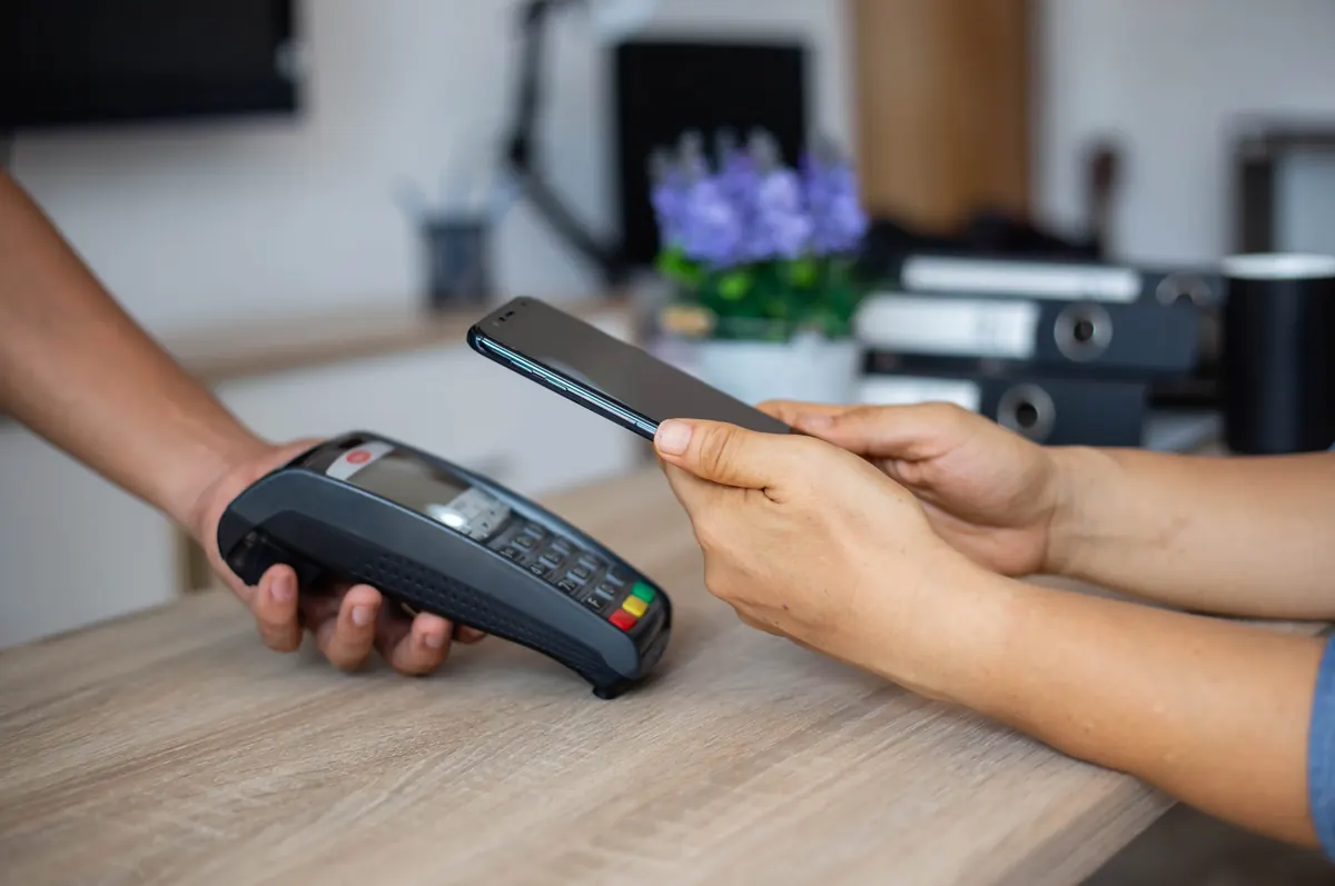 Contactless global payment transaction via mobile phone on a payment terminal at a checkout desk.