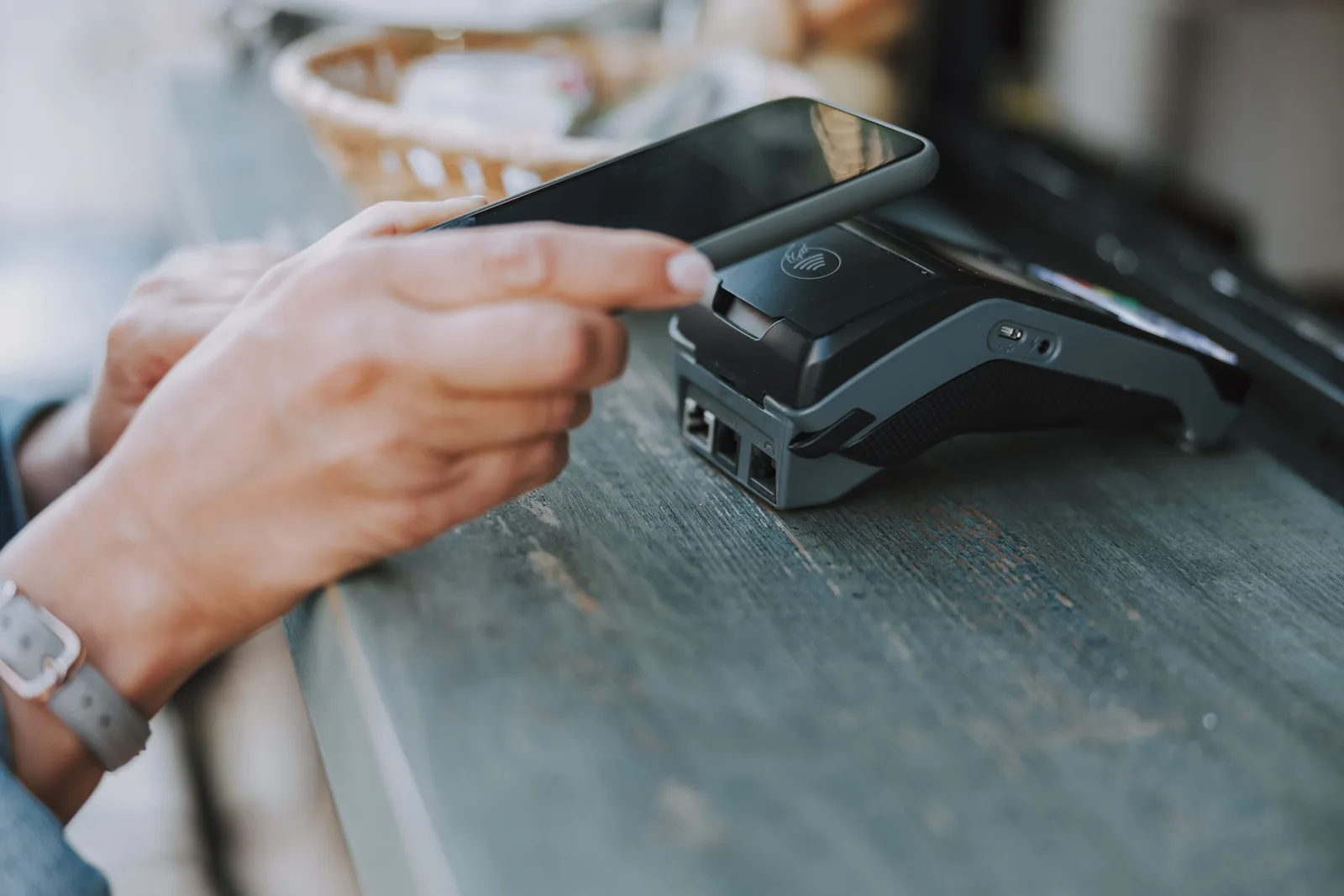 Hand paying a bill with a smartphone, representing embedded payments infrastructure.